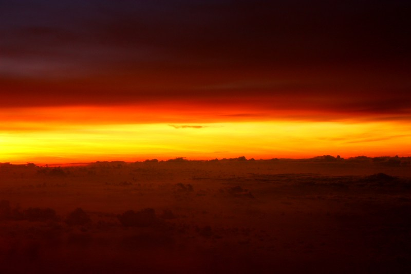 A cloudy sunset with a bright streak of yellow and two narrow streaks of red merging with black on either side