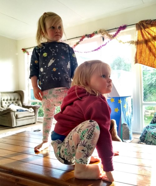 Children standing on table in sunny room watching looking to right