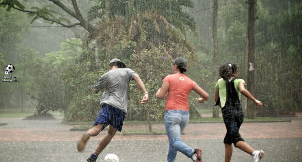 Teenagers playing football | soccer in the rain in Brazil with game icon on desktop
